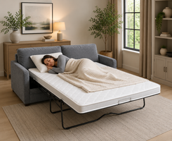 A gray upholstered sleeper sofa with white mattress