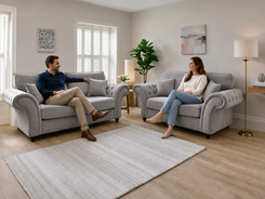 A man and a woman sit on matching light gray tufted armchairs 
