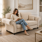 woman sits on a cream tufted loveseat